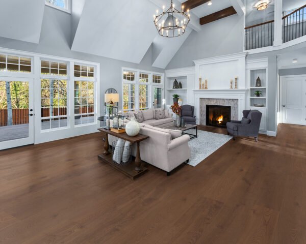 Spacious living room with Hawea hardwood flooring, featuring large windows, a fireplace, and elegant seating in a modern home.