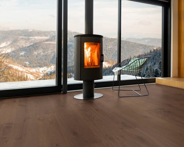 Modern room featuring Hawea hardwood flooring with a cozy fireplace and a scenic mountain view through large windows.